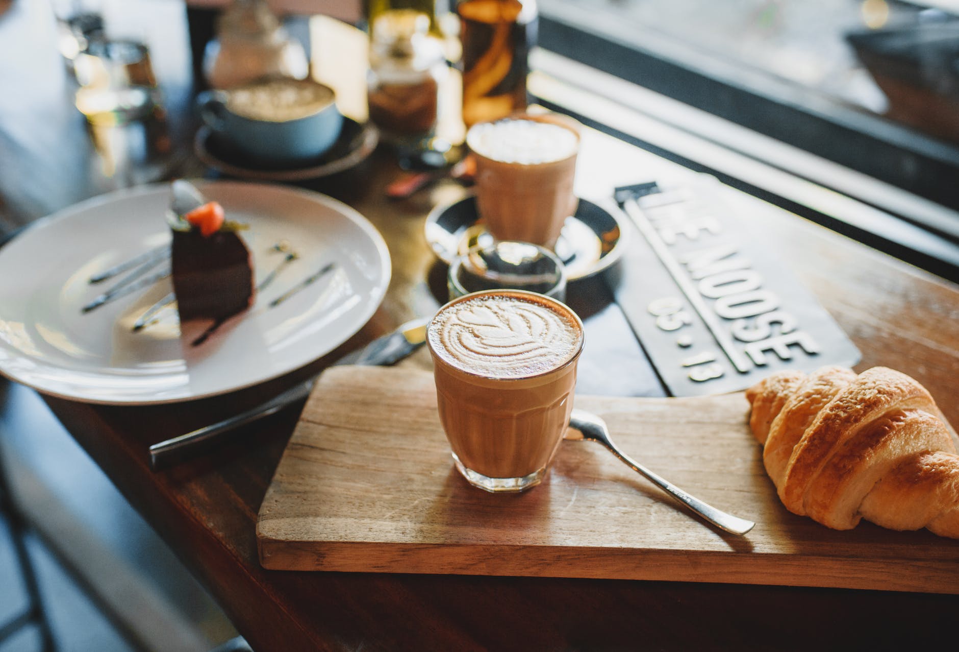 aromatic cappuccino with croissant on wooden board
